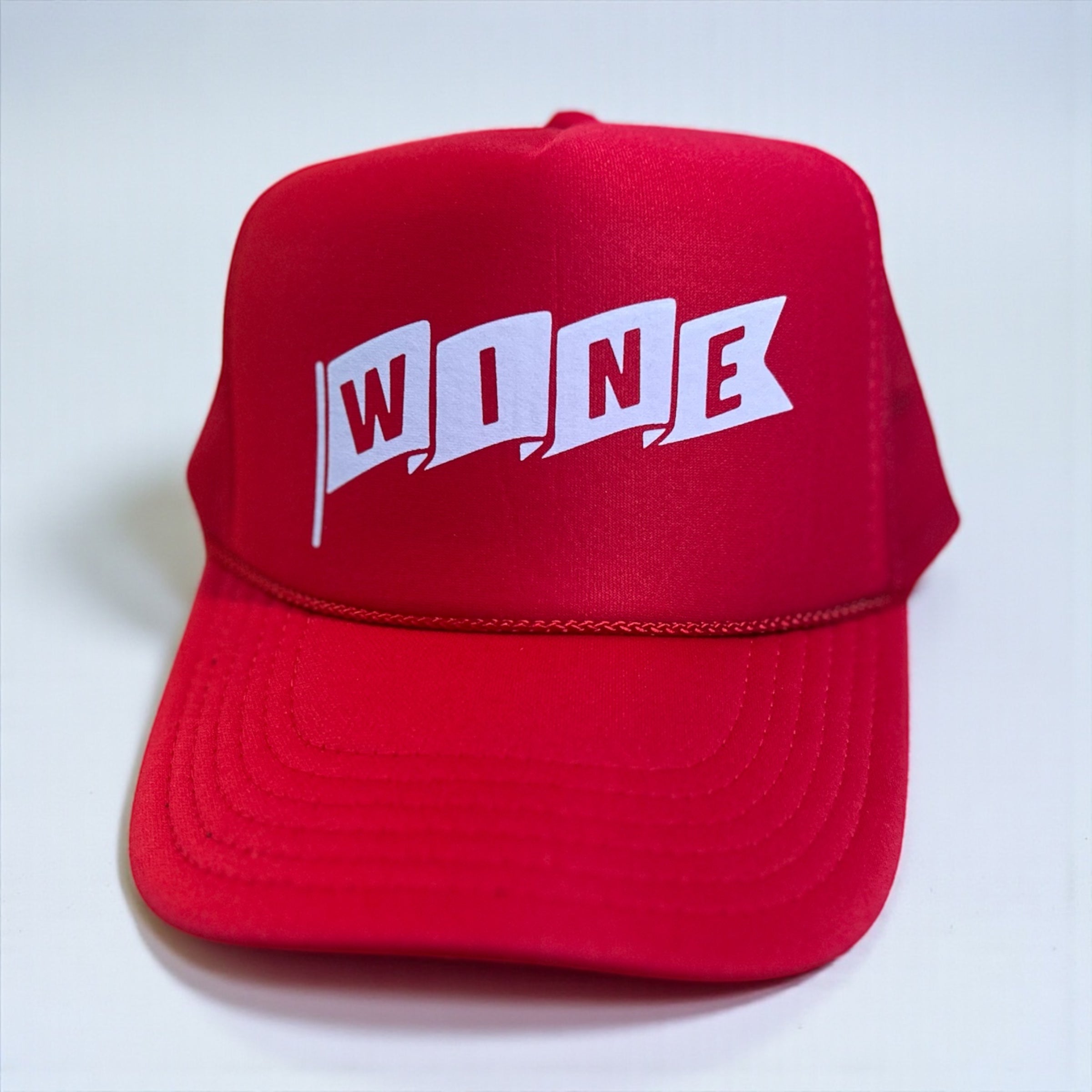 Red corkie foam trucker cap with 'WINE' printed on it against a white background
